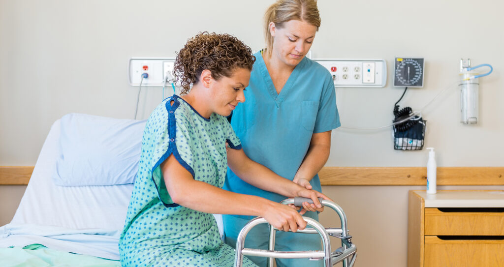 Mid adult female patient with walker while nurse assisting her in hospital